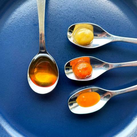 Three spoons on a blue plate. One (a sugar spoon) has Blowing Smoke's Molten Maple Hot Maple Syrup.The other three (coffee spoons) have Northern Lights (mild), Orange Sunshine (medium) and Magic Dragon (hot).