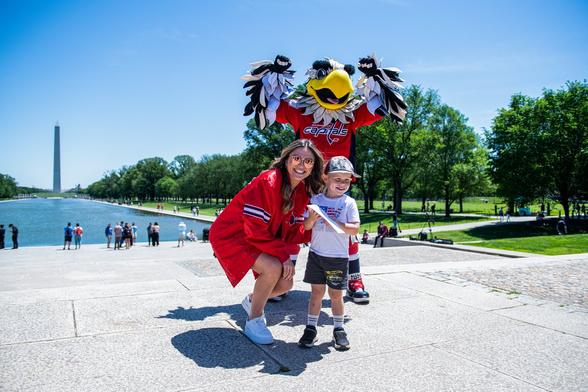 Annie Mae and Slapshot pose for a photo with a young Caps fan who won tickets to Game 5.