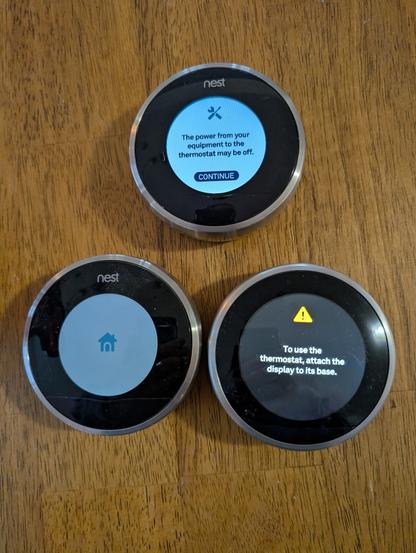 3 disconnected Nest thermostats on a table.