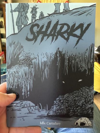 The image shows a TTRPG book titled "Sharky." The cover features a dark illustration with a prominent title at the top and a scene depicting figures on a hill with trees and flora below. The artwork has a monochromatic color scheme with shades of blue.