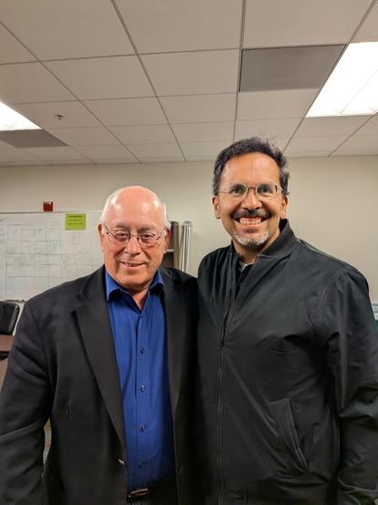 Baldemar next to your correspondent, in a union hall in San Francisco. Both are smiling after a good conversation.