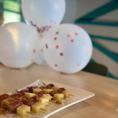 White balloons with glitter points in the background and some cheese and grape stick in the foreground