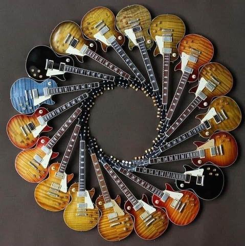 The image showcases a collection of electric guitars arranged in a circular pattern against a dark background. Each guitar exhibits a unique design and color, including variations of sunburst, natural wood, and solid colors like black and blue. The guitars have a classic double-cutaway shape, typical of models like the Gibson Les Paul. The arrangement emphasizes the diversity in guitar aesthetics while highlighting their shared design elements, such as the pickups, tuning pegs, and fretboards. The overall composition is visually striking and celebrates the beauty and variety of these musical instruments.