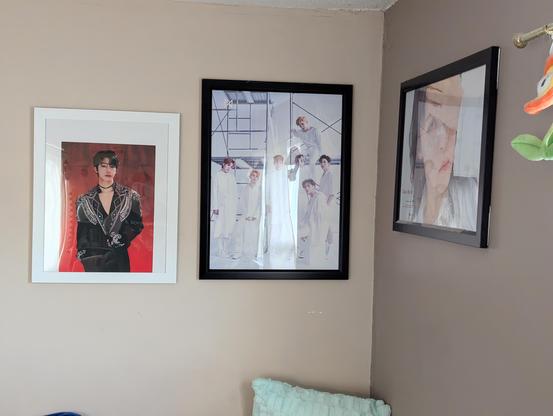 Image shows a wall with a Hyungwon poster and a Monsta X poster next to a wall with a Moonbyul poster.