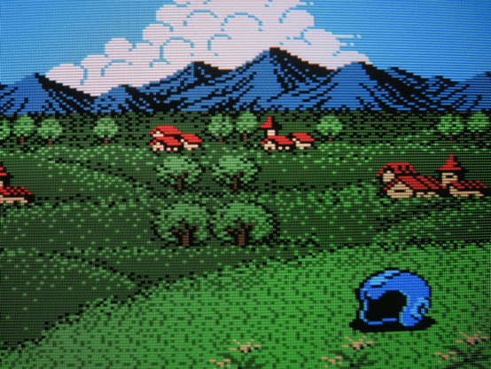 Mega Man's helmet lays upon a grassy knoll overlooking a peaceful rural village.