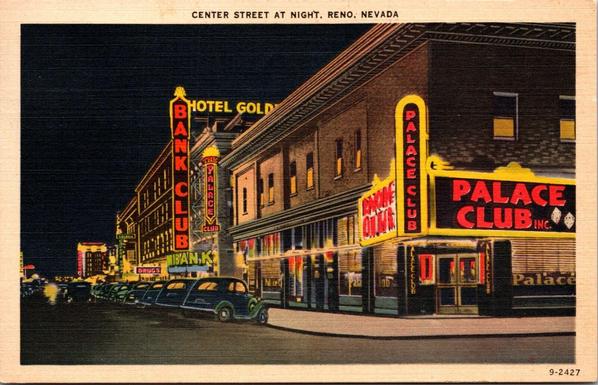 A view at night of a corner and streetscape full of neon lights.