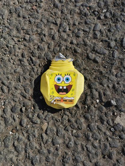 Litter. A squashed plastic drink bottle. It is bright yellow with Spongebob's smiling face on it.
