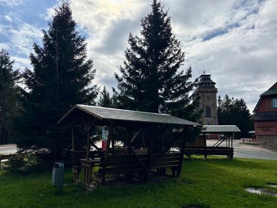 A picnic area with trees and a lookout tower in the background directly after a rain shower with clouds opening up again.