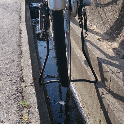 側溝の壁に自転車のスタンドを引っ掛けて立て駐輪している