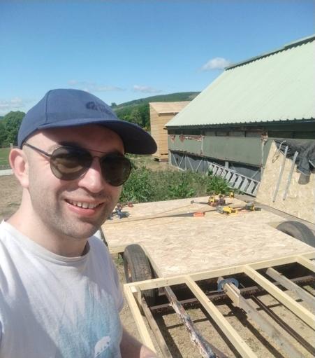 A selfie of me with a two wheel chassis that has been partially floored in the background.