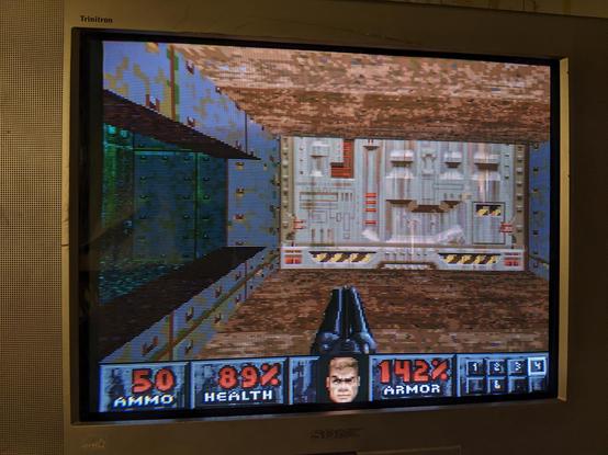Doom level opening. The player is holding a double barreled shotgun and looking at a door. 50 ammo, 89% health and 142% armor.