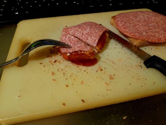 Sweet and sour pork sandwich being consumed via cutlery is disappearing quickly.
