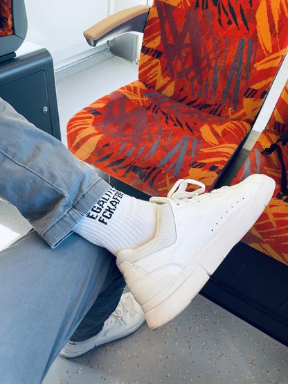 Das Bild zeigt eine Person, die auf einem öffentlichen Verkehrsmittel sitzt. Der Fokus liegt auf einem Fuß, der einen weißen Sneaker trägt. Die Socke ist weiß und hat den Text "FCKAFD" in schwarzen Buchstaben. Die Person trägt graue Jeans, die a den Knöcheln leicht abgeschnitten sind. Im Hintergrund sind Sitzplätze mit einem auffälligen orangefarbenen und roten Muster zu sehen, das an tropische Blätter erinnert. Der Boden ist grau mit kleinen, farbigen Flecken. Die Person sitzt auf einem Sitz mit einem Armlehnenarm aus Holz.

Die Person bin ich. 😆

Bereitgestellt von @altbot, privat und lokal generiert mit Ovis2-8B

🌱 Energieverbrauch: 0.205 Wh