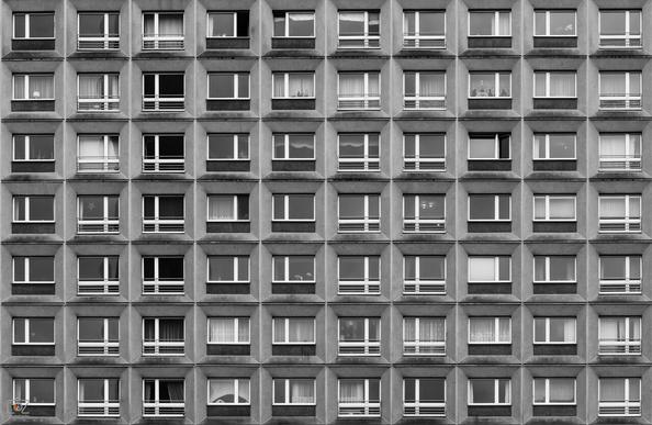 Black and white photograph of the front of a slab building with 10x7 evenly distributed windows.