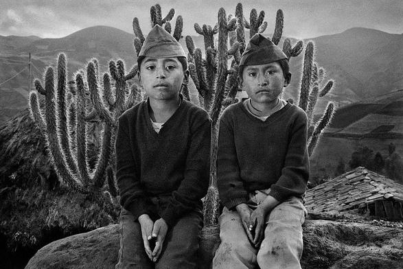 Black-and-white photo of two boys in Ecuador, 1982, with cacti and Andes mountains in background. Photo by Sebastião Salgado, the great Brazilian photojournalist who died today.