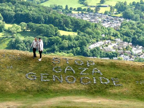 A mother and her son, carefully walking around the stone message, which sits on the grassy bank high above town
