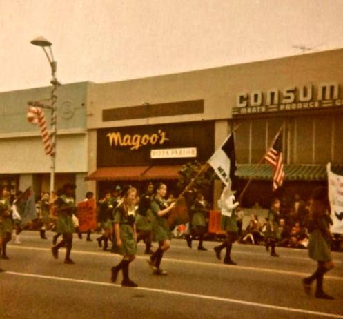 a girl scout troupe parades by Magoo's