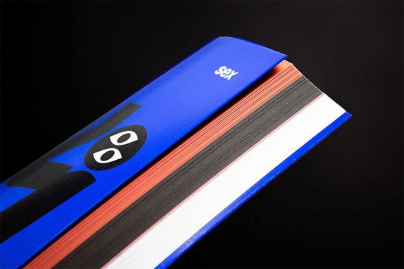 A close-up of a vibrant blue book showing colorful pages and a playful design on the cover against a dark background.