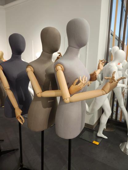 Three faceless store mannequins (fabric heads, torsos, and pelvises; wood or plastic articulated arms and hands) stand in a line. The first has arms raised as though in surprise or delight, the one behind is delicately fidding with the first's nipple region, and the third is reaching to grasp the second's arse at a Hudson's Bay store in Edmonton, Alberta, Canada where final contents and fixtures are for sale.