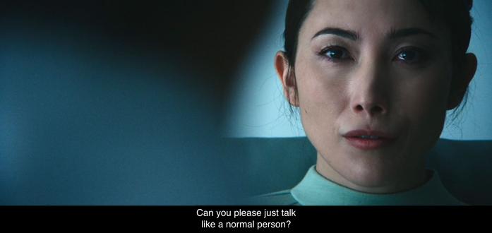 Close-up on Gemma whose face is on the right side of the frame. The back of Dr. Mauer’s head is on the left. She asks him, “Can you please just talk like a normal person?”