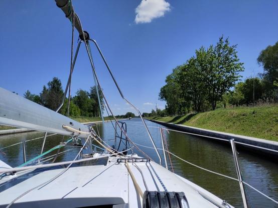 Same yacht, but with the mast down, going through a canal. Nice blue sky, sunny,