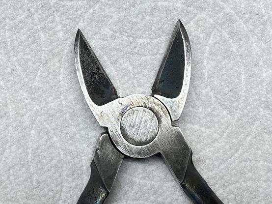 front? side of metal snips focusing on the blades, a silvery metal with black lines kinda.