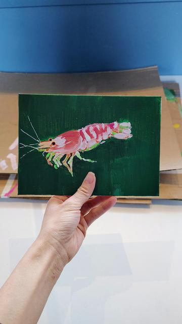 A shapelier painted orange pink shrimp on green.