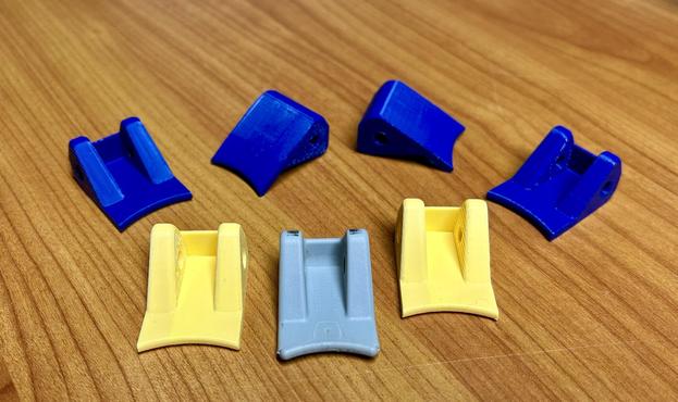 Six 3D printed replacement latches and one original.