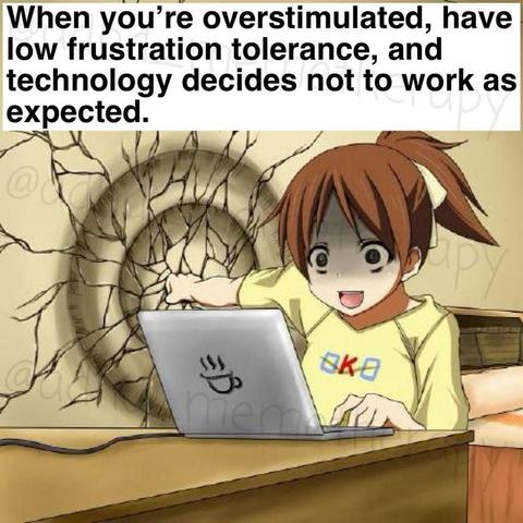 The image features an animated character with brown hair tied in a ponytail, wearing a yellow shirt with the letters "OK" on it. She is sitting at a desk with a laptop in front of her. The laptop has a sticker of a steaming cup on it. The character appears to be in a state of surprise or frustration, with her mouth open and eyes wide. Behind her, there is a wall with a large, circular crack emanating from the point where she is punching the wall. The text at the top of the image reads: "When you're overstimulated, have low frustration tolerance, and technology decides not to work as expected." The overall scene humorously depicts a moment of intense frustration, likely due to a technological issue.
