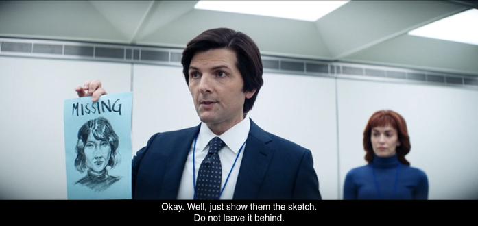 Mark S. holds up a sketch of Miss Casey on blue copier paper. Above in all caps is the word “MISSING”. Helly R. is in the background and he says, “Okay. Well, just show them the sketch. Do not leave it behind.”