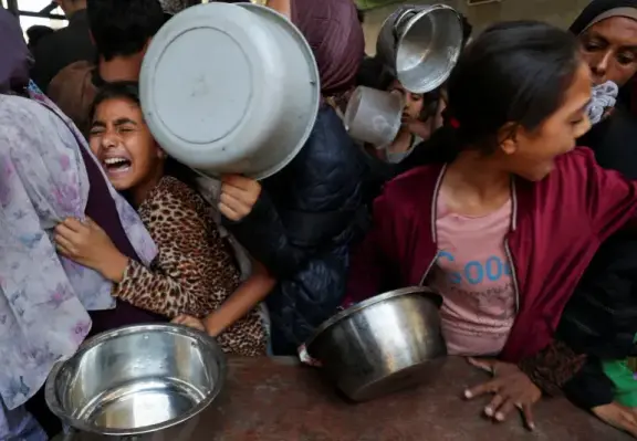 Palestinians wait to receive food cooked by a charity kitchen in Gaza City, May 21, 2025 [Mahmoud Issa/Reuters]