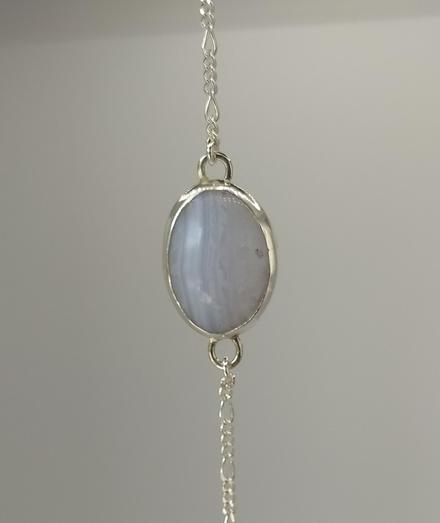 a light blue oval stone. it has a silver bezel and it's hanged from silver chain