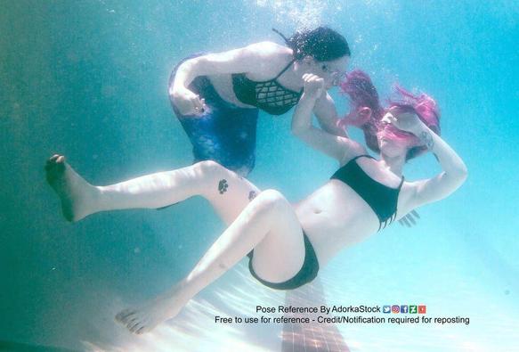 Two white women, one of which appears to be falling backwards and "drowning" (on the right) and the woman on the left is wearing a mermaid tail, trying to catch her.