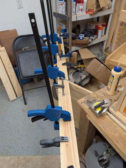A couple long pieces of wood clamped together with no fewer than 10 clamps. This is all in a dangerously untidy workshop.