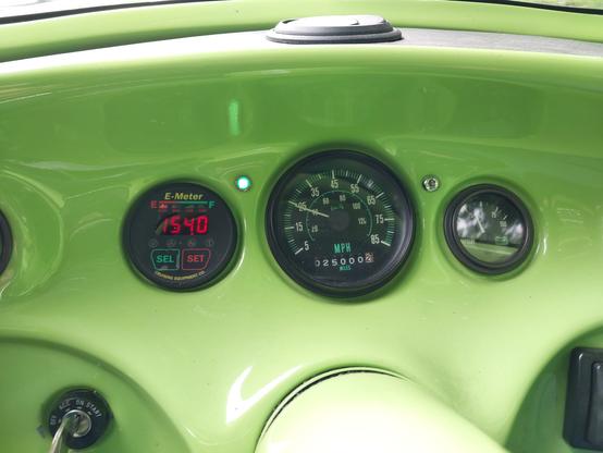 A minimalist instrument cluster set into a neon green dash. The center dial, the odometer, shows 25,000.2 miles.