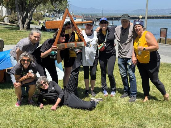 My sis (on the left, crouching with a beer and sunglasses) and the rest of her women's whaleboat rowing crew celebrating their combined seasonal victory, with some of them holding the trophy, a triangular wooden thing with an oar (or parts of one) affixed on either side. And yes, Soo there on the ground is kinda propping it up with her foot, sorta.