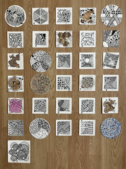 31 different Zentangle tiles laid out on a wooden floor, showing what I have drawn this month