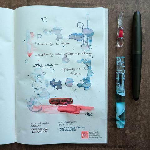 Photo of a haiku illustrated with ink in an open notebook next to two glass dip pens, one of which is just a tip, and a green cigar shaped fountain pen. The illustration has drops of silvery-purple-teal ink splotching and dripping like rain drops splattering and falling down a window, with hints of pink and red and a vivid red bus driving a long at the bottom. 
"becoming a bus
picking up pilgrims along
the way—spring rain drops"
- Poetry and art by Maiji/Mary Huang, humangray.com