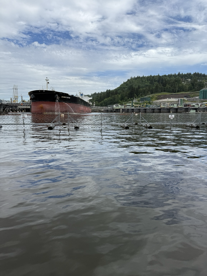 A red and black tanker ship, waiting to fill up with oil from the TMX pipeline. This small tanker is bound for Asian markets.