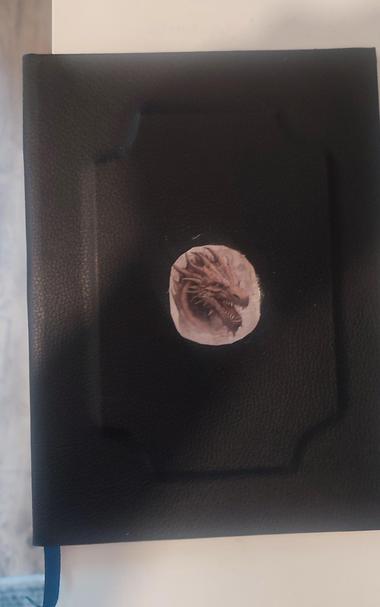 DAndD Character Sheet book cover. Faux Leather Black, with embossed frame. In the centre there is the sticker with a head of a dragon.