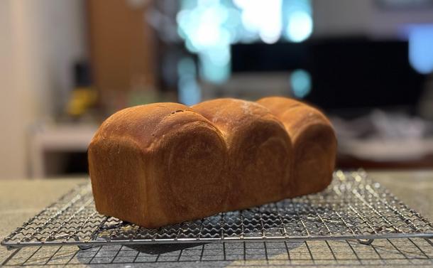 Three domed sandwich loaf on a cooling rack. It is uniformly a caramel brown.