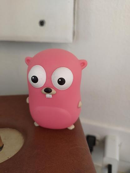A short pink figurine (plastic or some kind of resign maybe?) of the Go Gopher. ~3in tall.
