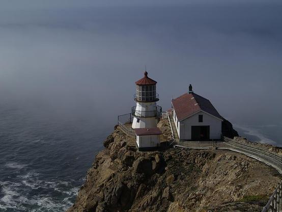 PT Reyes Lighthouse

This is an image of the Pt Reyes Lighthouse. This was captured at the point at Point Reyes National Seashore. The lighthouse reaches out into the Pacific Ocean on a small spit of land. 
There are over 300 steps to get down to the lighthouse.
On either side of the steps the land drops off into the ocean as seen on the left side of the image.
The lighthouse and supporting structures are white with a red roof. 
Out past the lighthouse is a bank of thick fog that is rolling in off of the ocean.