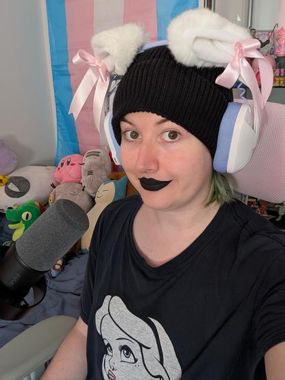 Revy wearing a black beanie and black lipstick and cat ear headphones
