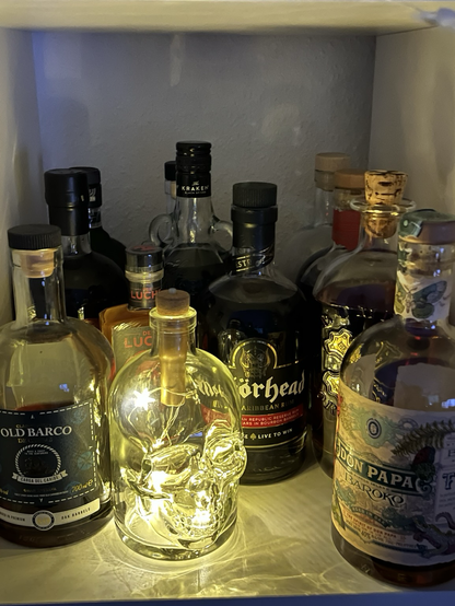 Ein Regal mit Rumflaschen und einer beleuchteten Totenkopf-Flasche