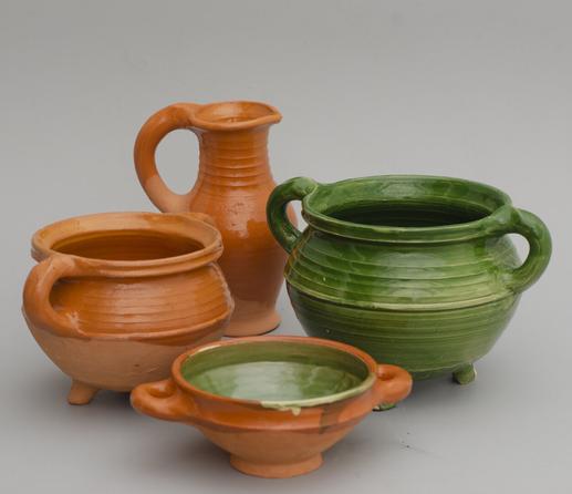 four pieces of pottery: a redware pitcher, a cauldron and a bowl with green glaze on the inside and a large green cauldron.