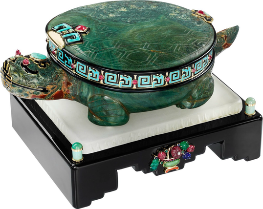 official auction photo, diagonal turn side profile on white background - shell lid closed  “It features a clock face, edged in gold with diamond-set hands in the form of a dragon, hidden inside a turtle's shell decorated with black and turquoise enamel and ruby cabochons, as well as carved rubies, emeralds and sapphires on the base.”