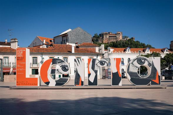 Colorful display for Leiria Film Fest 2024 in a sunny plaza, featuring large stylized letters and artistic eyes. Castle in background.