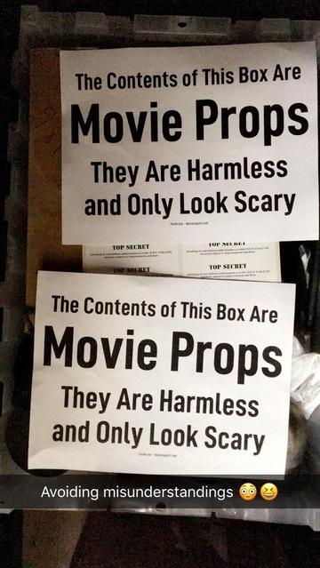 The image shows two identical signs placed on a box. The signs read, "The Contents of This Box Are Movie Props. They Are Harmless and Only Look Scary." Below the signs, there is a text overlay that says, "Avoiding misunderstandings" accompanied by two emojis: a face with a spiral eye and a winking face with a tongue sticking out.