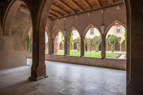 Inside of a medieval cloister viewed through a row of Gothic arches.